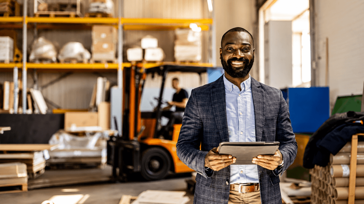 African warehouse business owner standing confidently in his stocked warehouse